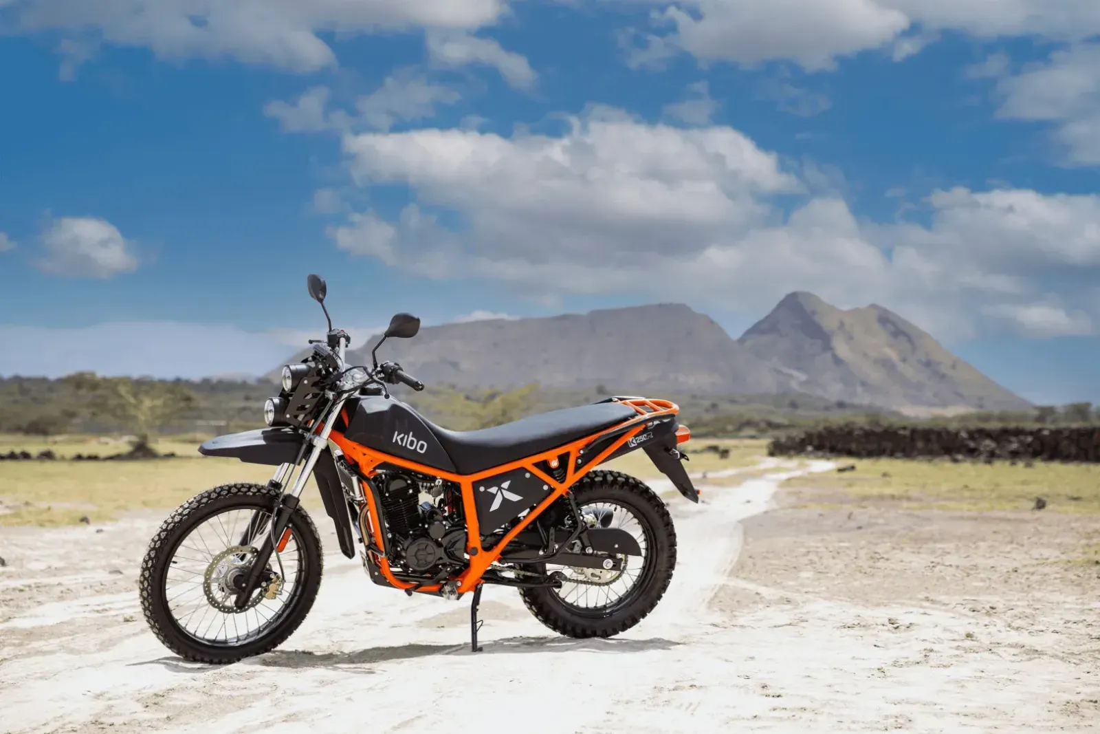Kibo 250R adventure motorbike parked on a gravel track with mountains behind