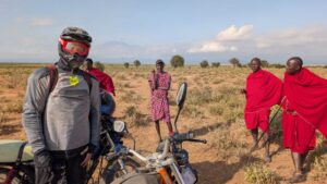 Motorbike rider meeting Maasai men on the plains of southern Kenya with Kilimanjaro in the background